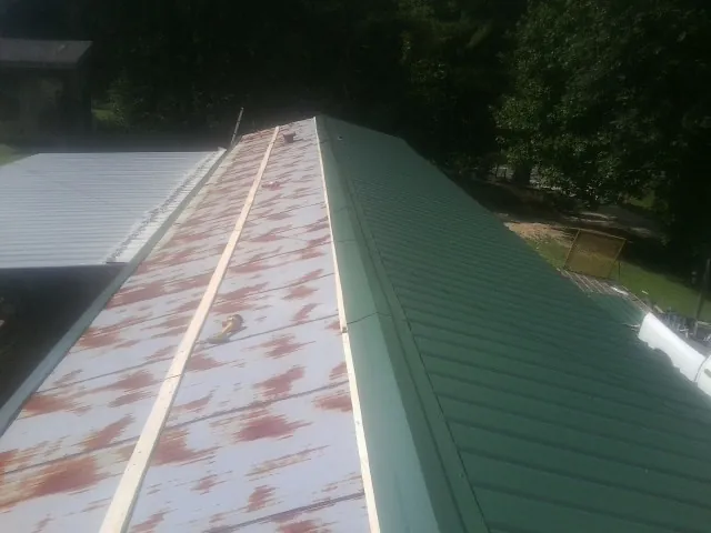 Old rusted panels beside newly installed green metal roofing — Wind Damage Roof Repair by Roofing Brothers in Mulino