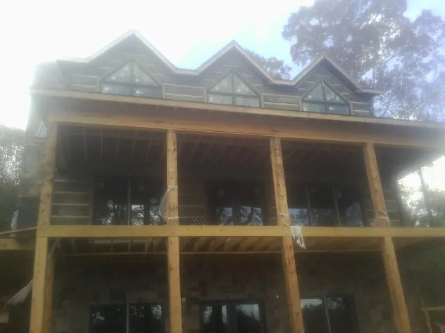 Dormers and porch framing on a large log home under construction — Roof Coating work by our crew in Mulino