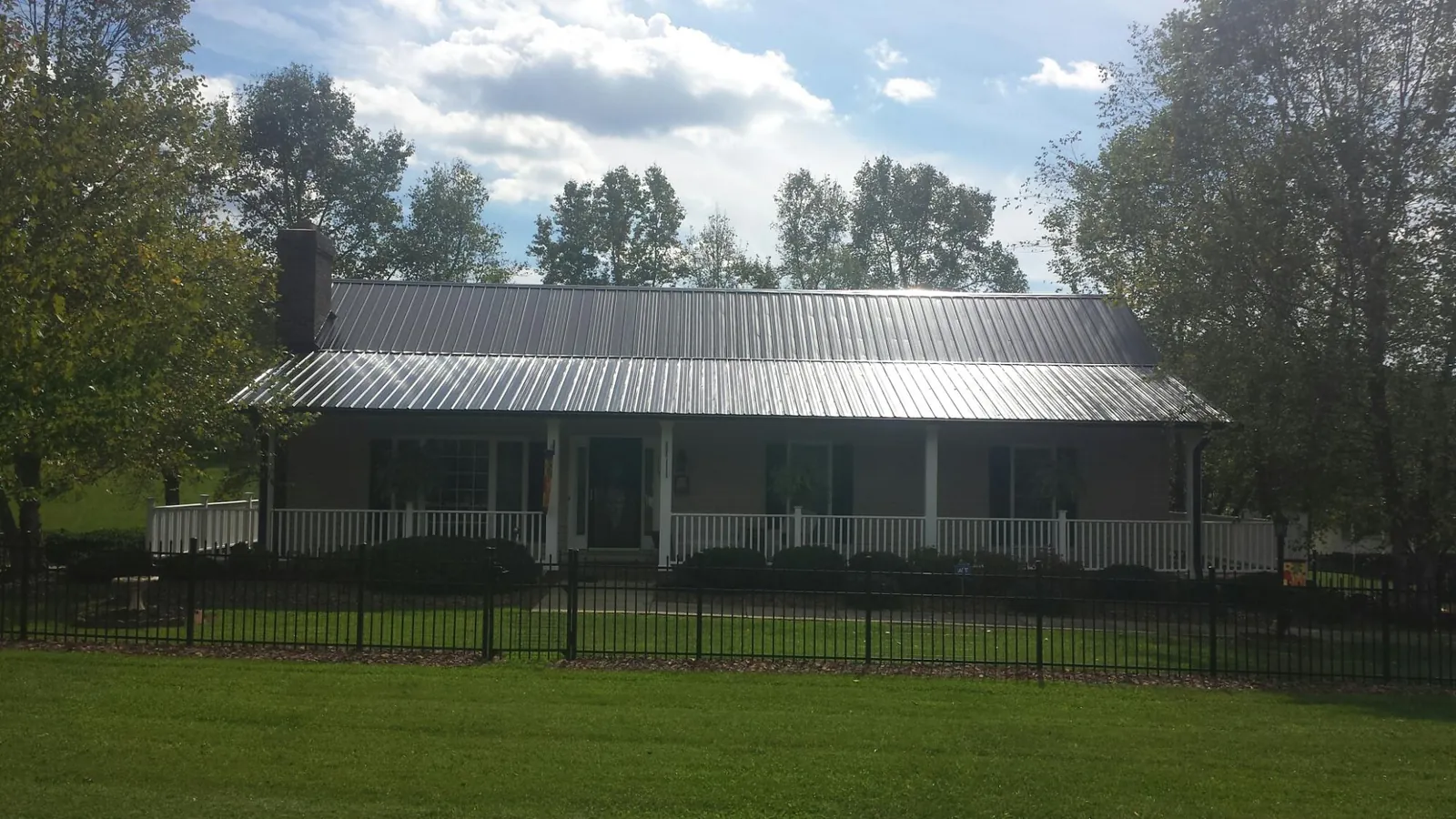 Gray metal roof on a brick ranch with a full width front porch — Gutter Guard Installation work by our crew in Mulino