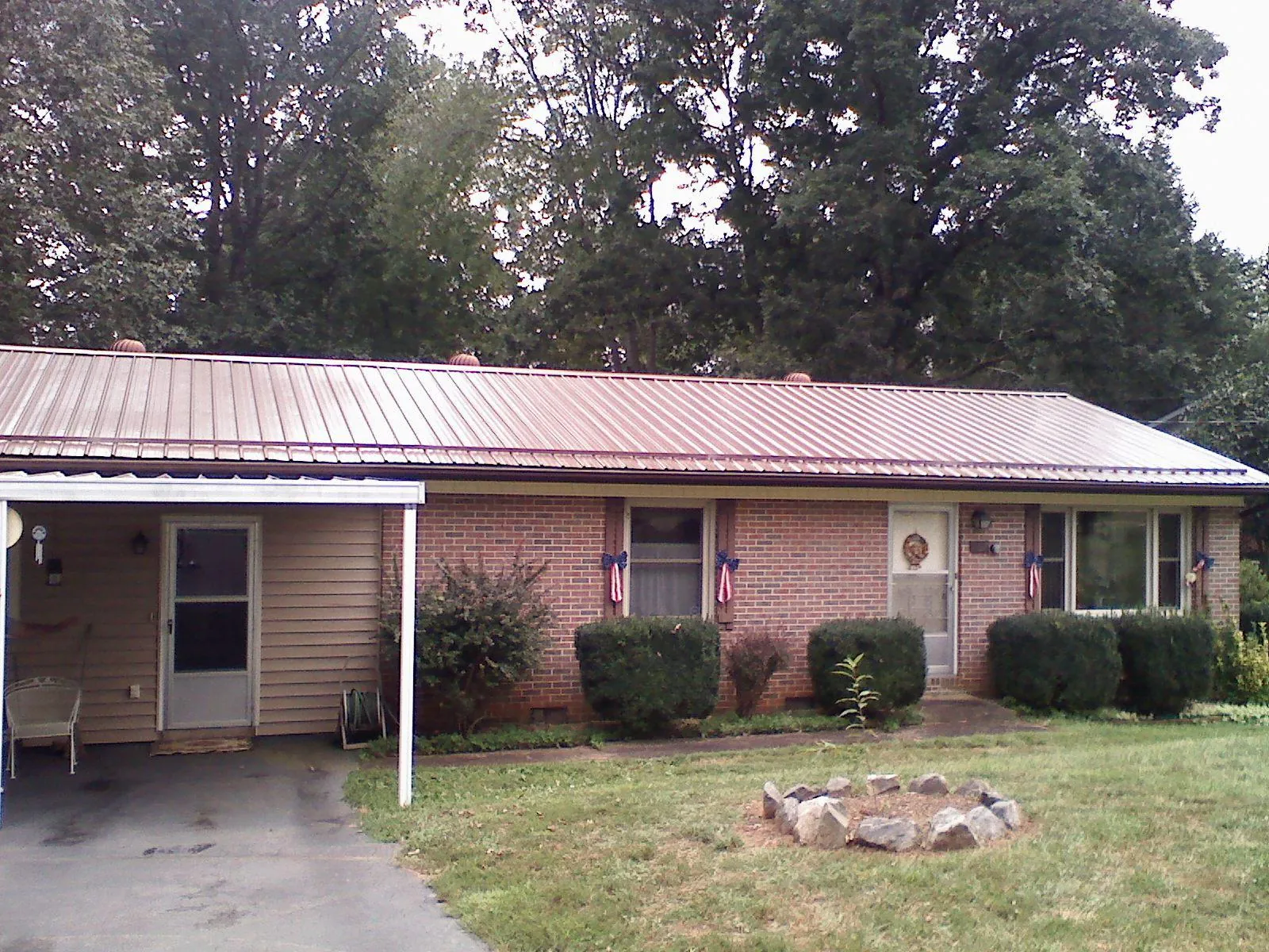 Bronze metal roof and carport on a brick ranch home — Roof Repair work by our crew in Mulino