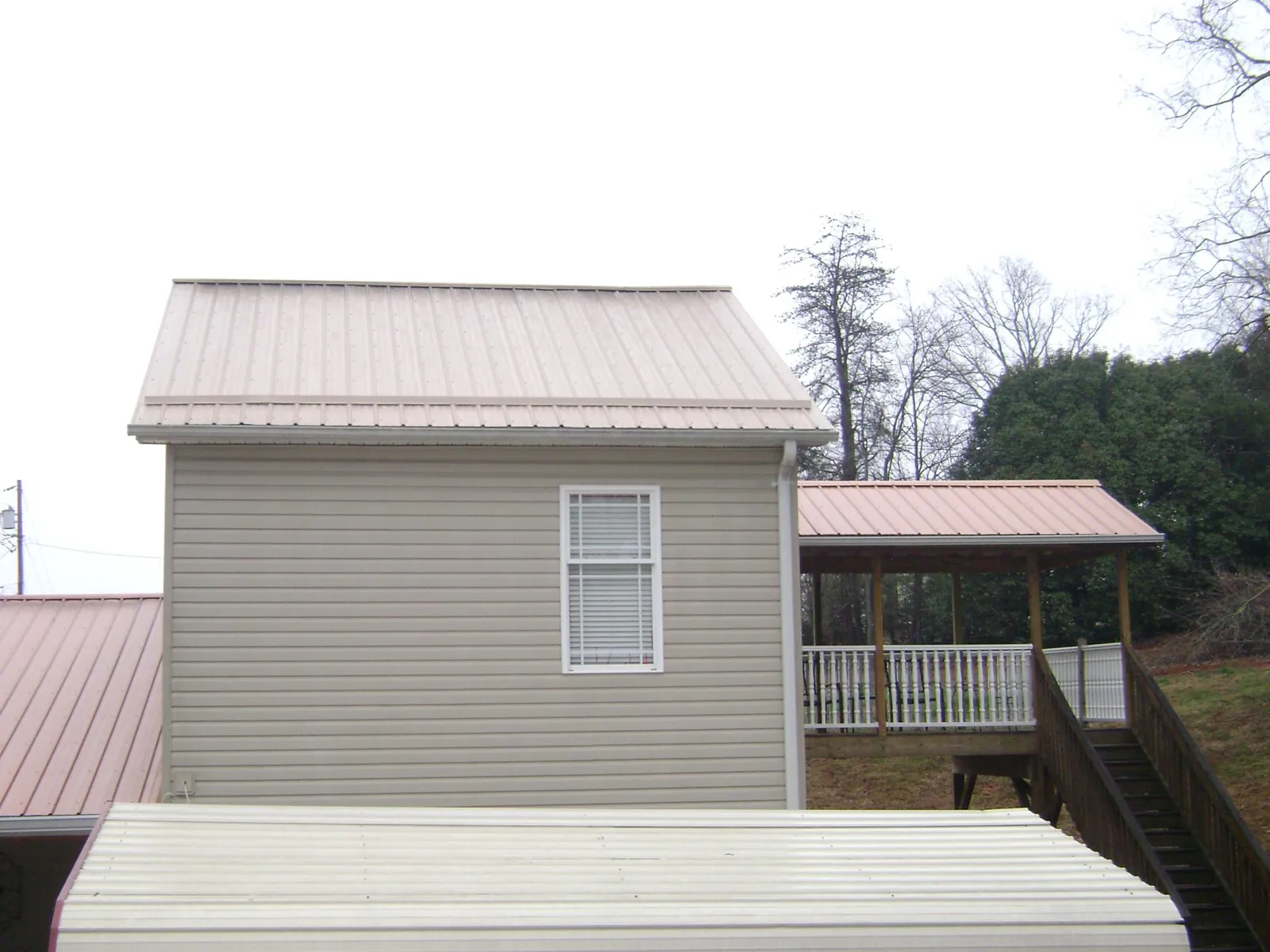 Tan metal roofs on a two story addition and attached porch, from a Roof Replacement job in Mulino