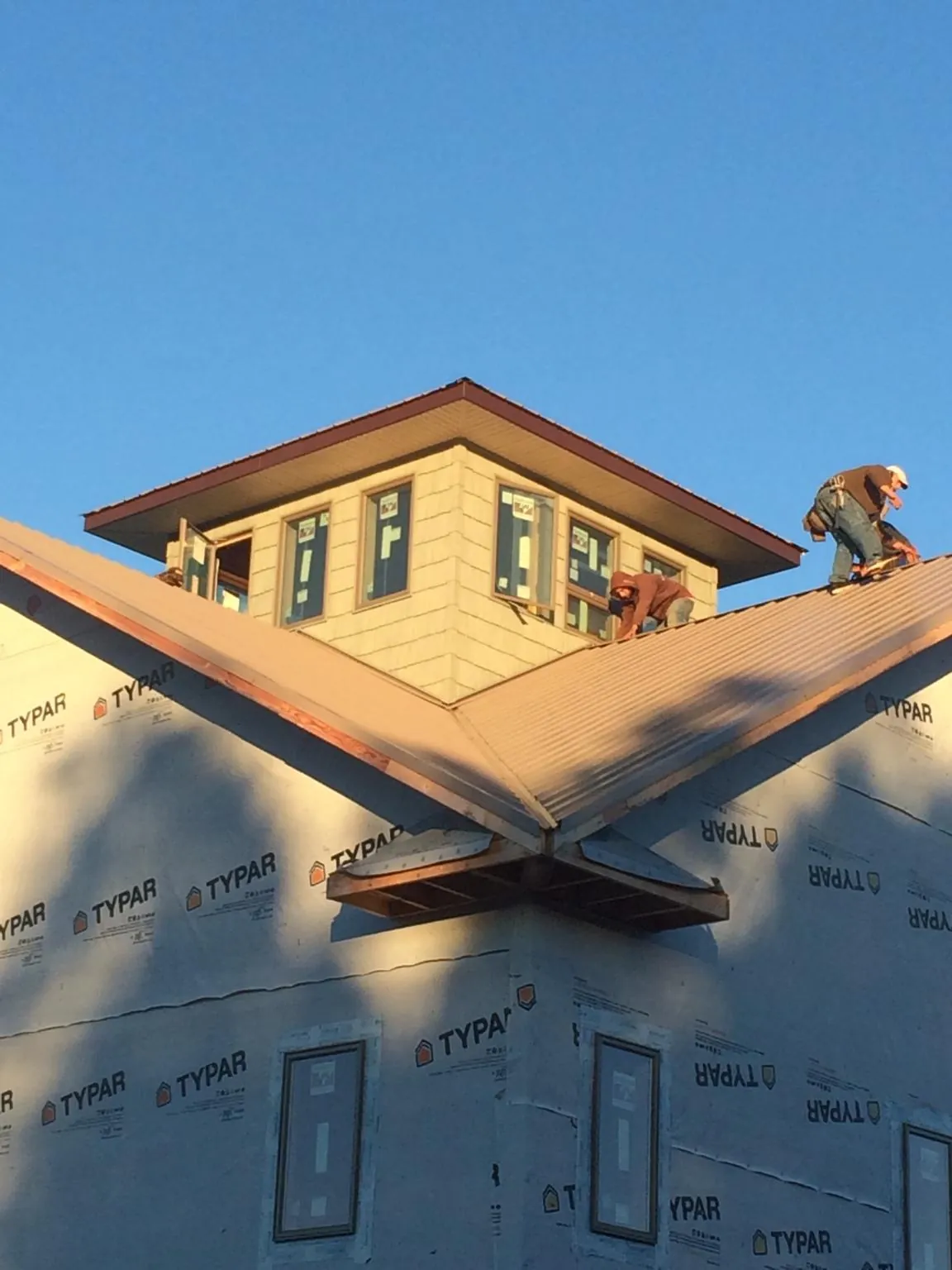 Roofers working around a rooftop cupola on a new metal roof at sunset — Roof Waterproofing in Mulino by Roofing Brothers